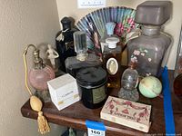 Overview of assorted giant store display perfume bottles, dummy perfume bottles, and lotion trio boxed set on wooden table.