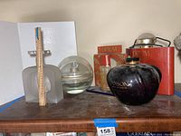 Overview of all five giant store display perfume bottles grouped on a wooden surface with ruler for scale