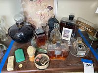 Giant perfume bottles and smaller dummy perfumes along with shaving brush and perfume box on wooden surface