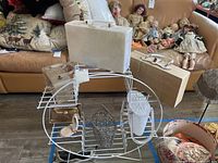 Wide view of metal display rack containing vintage handbags and accessories with porcelain dolls in background