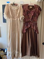 Photo of two vintage dresses hanging side by side, showing full length: brown sequin cocktail dress and tea-colored dress with lace trim