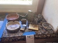 Full view of the lot showing vintage lighters and ashtrays on a granite counter by a window.