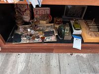 Wide shelf view showing many vintage perfume bottles of various shapes and sizes, along with boxed sets and accessories on a floral cloth.