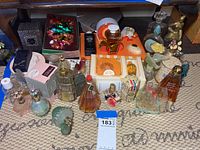 Photo showing wide assortment of vintage perfume bottles in various shapes, colors, and designs including boxed examples and decorative stoppers.
