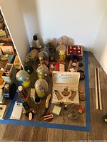 Overview of various vintage perfume bottles and tins laid out on floor corner