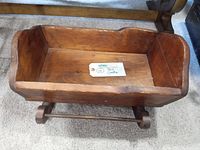 Top view showing handmade wooden cradle with smooth wood grain and minor scratches.