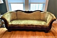 Front view of antique gold velvet sofa with carved wood trim, showing curved shape and fabric upholstery condition.