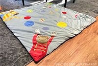 View of square baby play floor mat on floor showing monkey design at one corner with colorful polka dots.