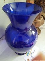 Blue glass vase viewed from an angle showing flared top and rounded body, reflective surface and rich blue color.