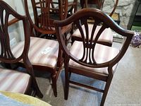 Front view of vintage mahogany Sheraton style dining chairs showing curved backs and pink striped seats