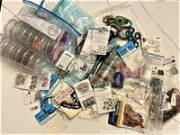 Overview photo showing assorted jewelry making supplies including beads in packages, bead cases, and metal findings