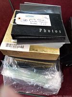 Stack of new photo albums including one labeled 'Photos' on black cover, some boxed and stacked.