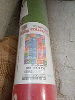 Photo of rolled and wrapped children's play room rug showing KC Dubs Playtime Collection label and size 8'2" x 9'10".