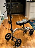 Full view of the Nova knee walker showing padded knee rest, frame, wheels, and handlebar with dual hand brakes.