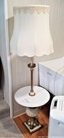 Full view of vintage floor lamp showing white fabric shade with lace trim, brass and marble column, round marble tabletop, and decorative base.