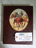 Front cover of the book showing leather embossing and the oval illustration of cowboys on horses.