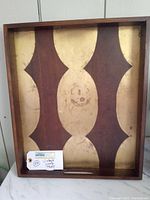 Full view of vintage wood tray showing brown and gold patterns with visible surface wear.