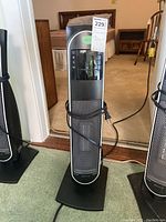 Full view of Bionaire air purifier tower with power cord wrapped around base, unit is tall and slim in black and silver colors.