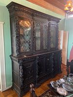 Front view of two-piece carved oak china hutch with four leaded glass doors above and four carved wooden doors below