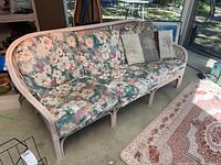 Full view of the bentwood couch with floral cushions and tree print throw pillows.