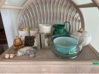 Photo of all items on a wicker surface including bowls, pitchers, candle warmer, figurines, bookends and shells.