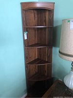 Full view of the tall corner shelving unit placed against a wall.