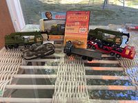 Seven Matchbox die cast vehicles displayed on glass table including two cranes, English tank, two trucks, MB21 Corvette Pacer in original packaging, and K111 Missile Launcher in box.