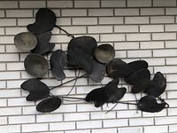 Full view of metal wall art depicting overlapping lily pad shapes mounted on exterior brick.