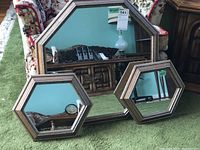 Set of three octagonal mirrors arranged on green carpet showing the large mirror and two smaller mirrors with wood-tone layered frames.