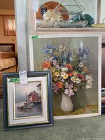 Framed oil painting of a seascape with boats, signed Max Savy, displayed next to a large floral print on floor.