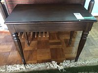 Front view of the wooden piano bench showing the dark stained top and turned legs.