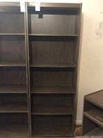 Full front view of wooden shelving unit standing empty, showing five shelf spaces and wood grain finish.