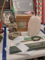 Full lot contents showing Buddha statue, Feng Shui candle set, white salt lamp, bracelet, and incense package.