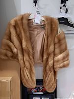 Natural brown mink stole hanging on a hanger showing the overall appearance of the fur wrap.