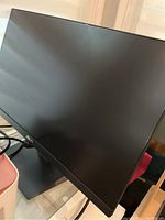 Front view of the Asus 24-inch monitor powered off, showing the screen and stand on a glass surface.