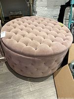 Front side angle showing tufted button velvet upholstery and round shape.