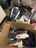 Lot overview showing purses, shoes, backpacks, and blue glass cases in a box and on the floor
