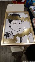 Full view of framed Audrey Hepburn art print with gold accents, showing overall condition and framing.