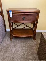 Full front view of rattan nightstand with drawer and lower shelf, showing woven rattan texture and round metal drawer knob.