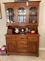 Front view of the closed wooden china hutch showing three glass-paned doors on the upper section and drawers and cabinets below.