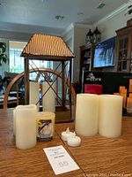 Wide shot showing all flameless candles and decorative metal stand on wooden table with living room in background