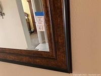 Close-up detail of the dark brown wooden frame of the large rectangular mirror showing its texture and layered design.
