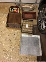 Photo showing all trays and fruit basket placed on garage floor near car wheel.
