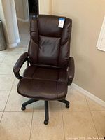 Front view of brown executive high back office chair on tiled floor.