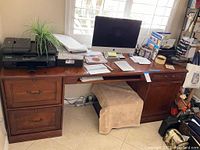 Full view of the wooden executive desk showing the desktop with items, printer, and computer monitor.