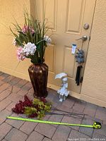 Tall decorative vase with faux floral stems arranged inside next to a little girl statue and turtle wind chime.