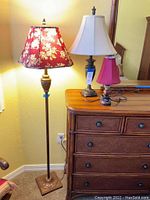 Full view of the 62" floral floor lamp beside wooden dresser with two table lamps on top.