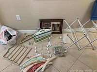 Overview of laundry related items on floor including hangers, drying rack, laundry bag, and framed laundry wall art.
