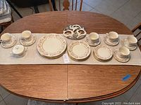 Full set of Lenox Helmsley china laid out showing plates, cups, saucers, sugar bowl, and metal trivet on table.