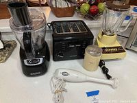Shows all five small kitchen appliances on a kitchen counter including food processor, toaster, blender, chopper, and immersion blender